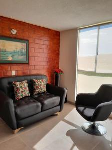 a living room with a leather couch and a chair at Apartamento con vista al lago in Paipa