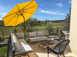 a patio with a table and a yellow umbrella at Villa Magrado in Entrecasteaux