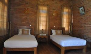 2 letti in una camera con muro di mattoni di Trinity Family Inn a Nyaung Shwe