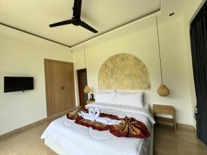 a bedroom with a bed with white sheets and a fan at La Danu Villa in Kubupenlokan
