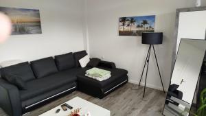 a living room with a black couch and a table at Schöne Ferienwohnung/Pendlerwohnung in Uelzen