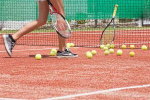 a person with tennis balls on a tennis court at Contaratos Beach Hotel in Naousa