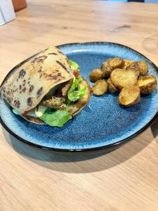 a blue plate with a sandwich and potatoes on a table at Maison d'Hôtes Ty Belle in Saint-Guen