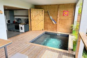 una piscina en una terraza de madera con cocina en Bungalow Cosy, en Grand-Bourg