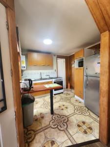 a kitchen with a table and a refrigerator at Céntrica y Hermosa Casa Apartamento in Puerto Varas
