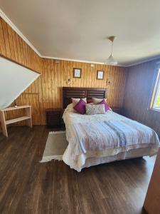 a bedroom with a bed with a wooden wall at Céntrica y Hermosa Casa Apartamento in Puerto Varas