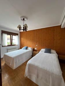 Dos camas en una habitación con paredes de madera. en Casa con jardín a pie de playa y montaña, en Panes