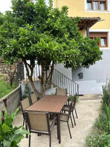 una mesa de madera y sillas bajo un árbol en Casa con jardín a pie de playa y montaña, en Panes