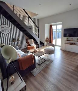 a living room with a couch and a staircase at Gite La maison du 37 avec terrasse et jardinet in Breteil