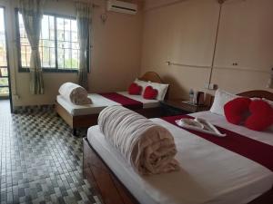 a hotel room with three beds with red pillows at Sauraha Inn in Sauraha