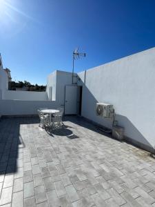 a patio with a table and chairs next to a wall at Apartamento Vitelio in Carmona
