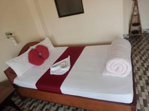 a bed with two towels and red pillows on it at Sauraha Inn in Sauraha