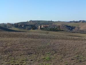 an empty field with a house in the distance at Podere Cedrola in Asciano