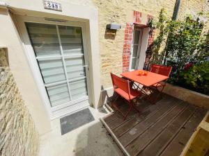 a red table and chairs on a wooden deck at Maison de ville avec spa privé in Courseulles-sur-Mer