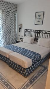a bedroom with a large bed with blue and white sheets at Central Acquamarine suite whit terrace in Sharm El Sheikh