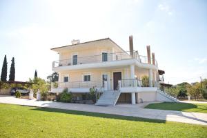 a large white house with a porch and a lawn at Villa Eva στην περιοχή Ερέτρια in Eretria