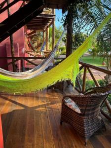 a hammock and a chair on a wooden floor at Chaleville Coqueiro 1001 in Luis Correia
