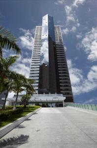 a large tall building with a palm tree in front of it at Beach Class International - Beira Mar - Boa Viagem in Recife