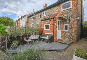 ein Backsteinhaus mit einer Terrasse davor in der Unterkunft Caines Cottage in Saxmundham