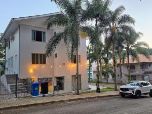 a white house with palm trees in front of it at Casa das Palmeiras in Piratuba