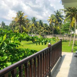 a balcony with a view of a park with palm trees at Oneida Villa & Restaurant in Talpe