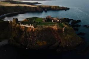 a castle on a cliff in the ocean at Stonehaven Centre - Dunnottar Apartment in Stonehaven
