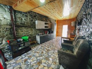 un soggiorno con parete in pietra e una cucina di Guest House Waterfall a Mazeri