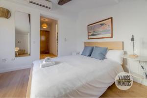a bedroom with a large white bed with blue pillows at Despertar en Madrid para 2, Carretas 25 in Madrid