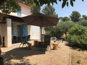 eine Terrasse mit einem Sonnenschirm und zwei Stühlen und einem Tisch in der Unterkunft Le NORD AU SUD pour 2 personnes in Villecroze + 9 Fotos