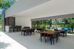 eine überdachte Terrasse mit Tischen und Stühlen sowie einem Pool in der Unterkunft Casa Holkan, Playa del Carmen in Playa del Carmen