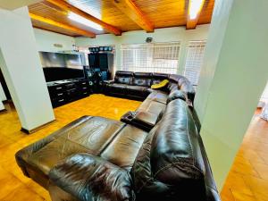a leather couch in a living room with a television at Honeyhills Excellence Resort E in Roodepoort