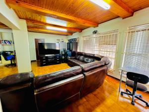 a living room with a leather couch and a flat screen tv at Honeyhills Excellence Resort E in Roodepoort +4 photos