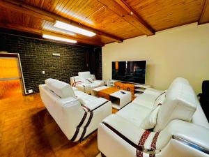 a living room with white couches and a flat screen tv at Honeyhills Excellence Resort E in Roodepoort