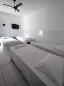 um quarto com três camas e um ventilador de teto em HOSTEL Bom Gosto em Canavieiras