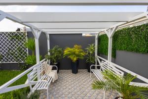 a patio with two white benches and plants at VILLA HELENA Amber Apartment in Caniço +54 photos