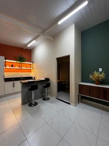 una oficina con escritorio y dos taburetes en una habitación en Loft Sulfurosa - 800m do Parque das Águas, en São Lourenço