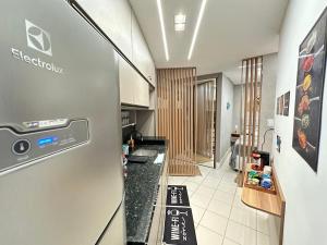 a kitchen with a refrigerator and a white tile floor at Muro Alto Marulhos flat cinematográfico in Porto De Galinhas