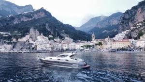 a white boat in the water with a city at AIR OF HOME Amalfi-Sorrento Coast in Angri