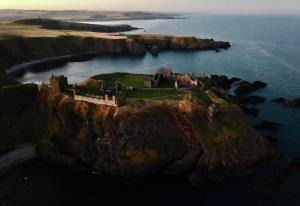 an island in the ocean with a castle on it at Stonehaven Centre - Carron Apartment in Stonehaven