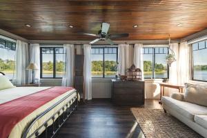 a bedroom with a bed and a couch and windows at Stay at Little River in Gloucester