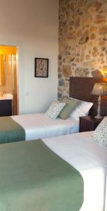a bedroom with two beds and a stone wall at Casa Pita Caminha in Caminha