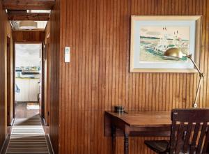 a hallway with a wooden wall with a desk and a picture at Stay at Little River in Gloucester
