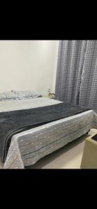 a bed with a black blanket on it in a bedroom at Centro próximo à rua das pedras in Búzios