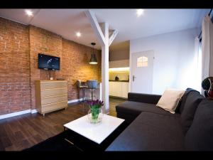 un salon avec un canapé et un mur de briques dans l'établissement Apartmenty Mariacka 20 -Self Check-In 24h -Loud on the weekends - by Kanclerz Investment, à Katowice