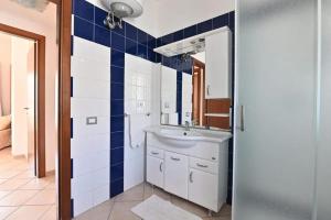 La salle de bains est pourvue d'un lavabo et de carrelage bleu et blanc. dans l'établissement Sea View Apartment 90 m² in South Sardinia, à Villasimius 23 autres photos