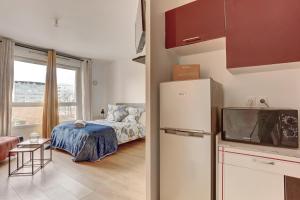 eine Küche mit einem Kühlschrank und ein Schlafzimmer mit einem Bett in der Unterkunft Le Sully - Mantes la jolie in Mantes-la-Jolie
