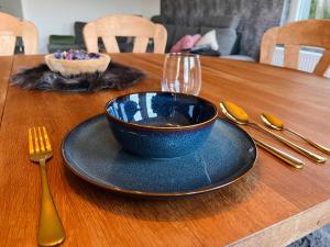 a wooden table with a blue bowl and a plate and a fork at Ferienhaus Zum Brand in Butgenbach +22 photos