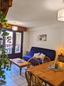 a living room with a blue couch and a table at Appt T3 calme bord du lac avec piscine in Loudenvielle