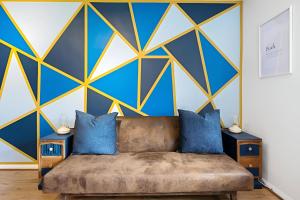 a bedroom with a couch and a blue and yellow wall at Comfortable Studio Apartment, Maidstone in Maidstone