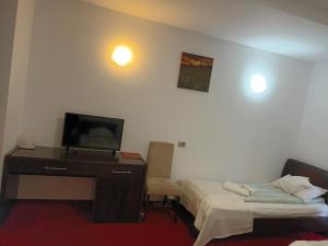 a room with two beds and a desk with a television at Hotel Transilvania Zalău in Zalău
